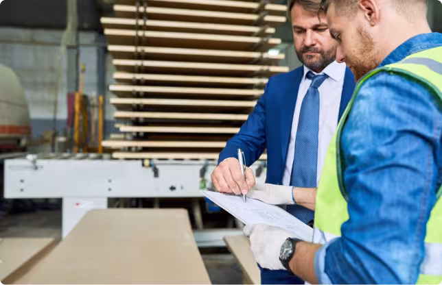Manager and factory worker reviewing production documents on the shop floor