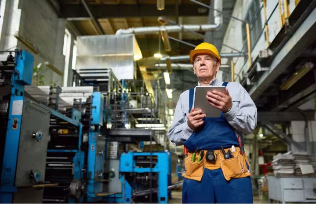 Industrial technician holding a tablet on a factory floor